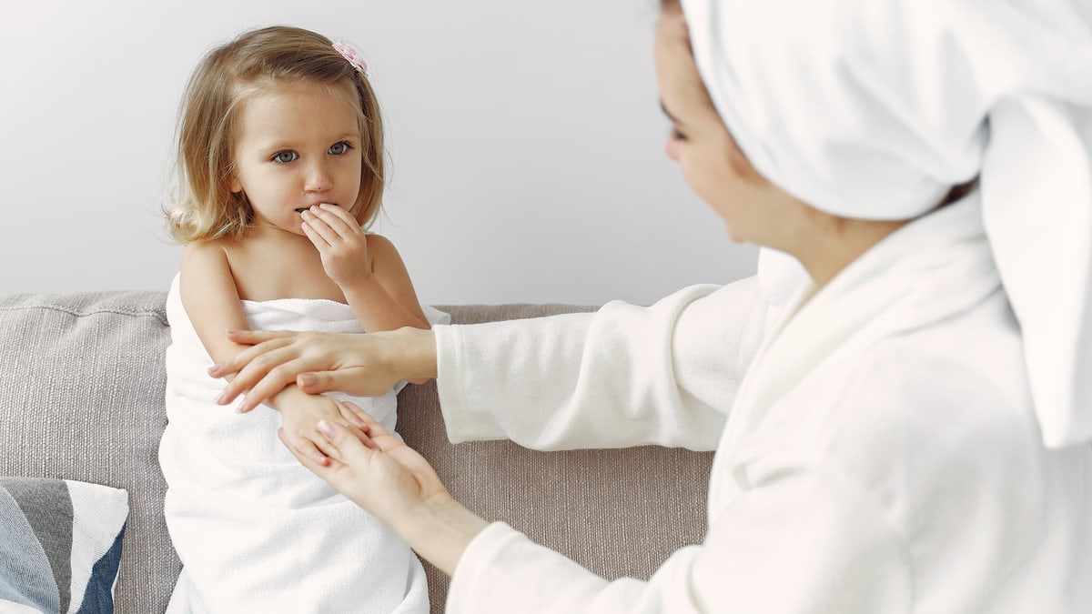 A mother gently interacts with her daughter wrapped in a towel, showcasing warmth and love.